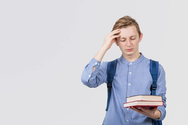 Gestresster Teenager schaut mit der Hand auf dem Kopf zu Büchern — Stockfoto
