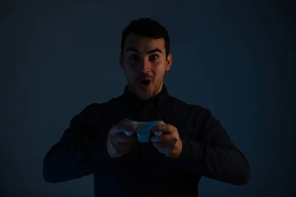 Fröhlicher junger Mann spielt Videospiele isoliert auf grauem Hintergrund — Stockfoto