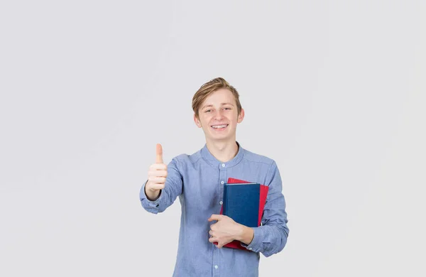 Šťastný dospívající chlapec s palcem nahoru a s knihami v ruce. Kniha — Stock fotografie