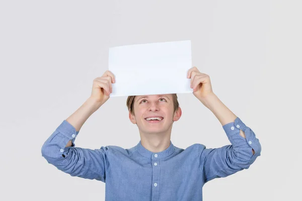 Ein lächelnder Teenager, der ein weißes Papier über seinem Kopf hält. Bildung — Stockfoto