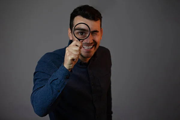 Hombre sonriente con lupa sobre fondo gris. Curioso yo — Foto de Stock