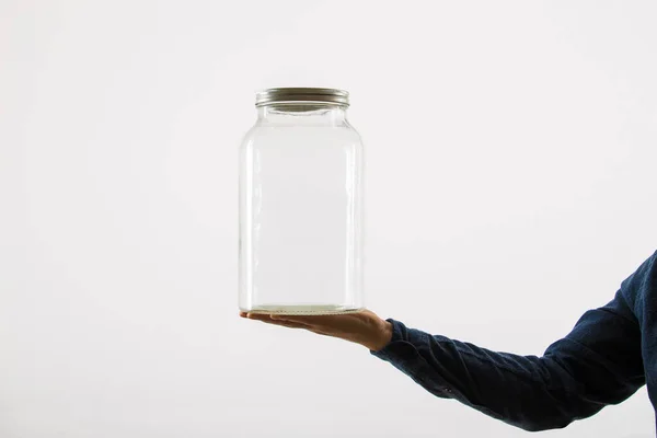 Primer plano de la mano de la persona sosteniendo un frasco de vidrio vacío aislado sobre — Foto de Stock