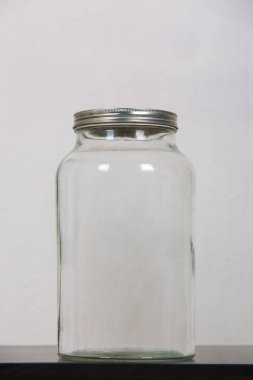 Boş bir kavanozun fotoğrafını çek, masanın üstünde, bir meta ile kapalı.