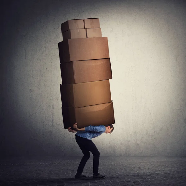 Bent down guy carrying a lot of big heavy boxes on his back. Ove — Stock Photo, Image