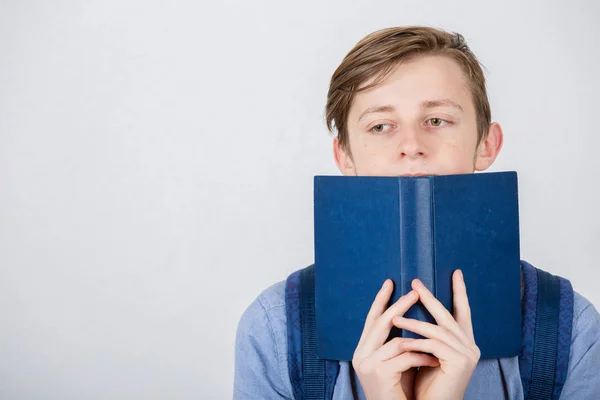 Gestresste Studentin bedeckt das halbe Gesicht mit einem aufgerissenen blauen Buch. dif — Stockfoto