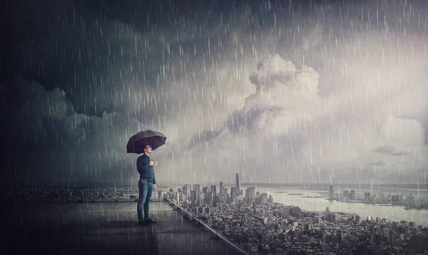 屋根の上で嵐の下に立っている思慮深いビジネスマン — ストック写真