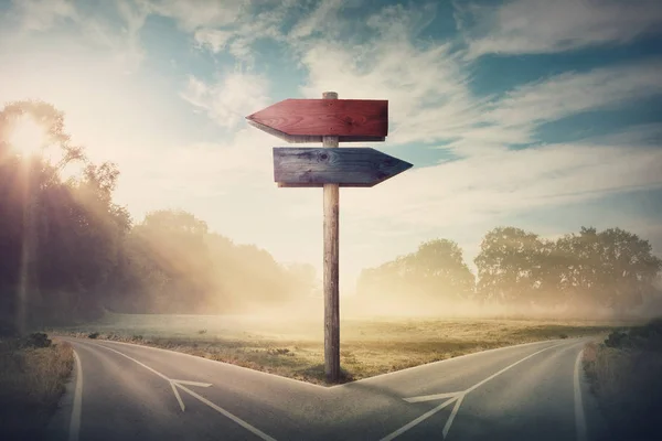 Surreal landscape with a split road and signpost arrows showing — Stock Photo, Image