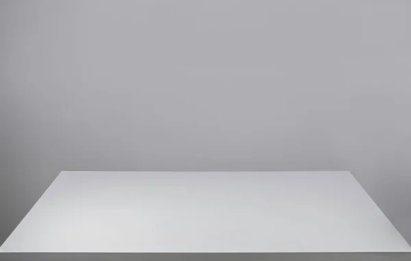 Mesa de mesa branca vazia e uma parede cinza em branco para espaço de cópia. Gra. — Fotografia de Stock