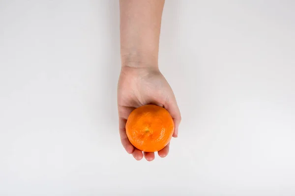 Primer plano de una mano humana sosteniendo una mandarina de naranja fresca o cl — Foto de Stock