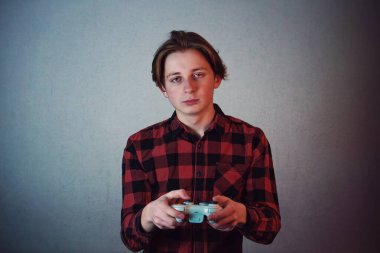 Exhausted teenage guy playing video games isolated on grey wall 