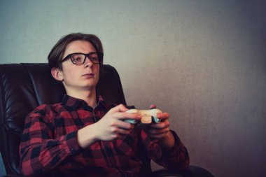 Serious adolescent boy playing video games late night seated rel