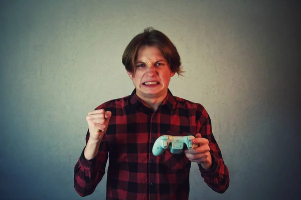 Розроблений хлопчик-підліток грає у відеоігри ізольовані на сірій стіні — стокове фото