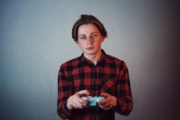 Уставший подросток, играющий в компьютерные игры, изолированные на серой стене — стоковое фото