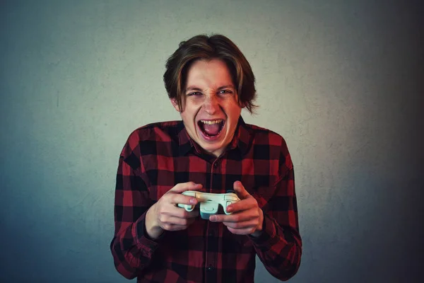 Фокусований підліток хлопчик грає у відеоігри ізольовані на сірій стіні backg — стокове фото