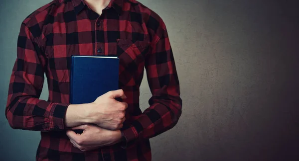 Perto de um adolescente a segurar um livro azul perto do corpo. Educa — Fotografia de Stock