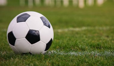 Klasik futbol topu, tipik siyah-beyaz desenli, stadyum sahasının beyaz çizgisi üzerine yerleştirilmiş. Yeşil çimlerin üzerinde fotokopi alanı olan geleneksel futbol topu.