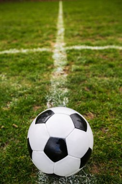 Klasik futbol topu, tipik siyah-beyaz desenli, stadyum sahasının beyaz çizgisi üzerine yerleştirilmiş. Yeşil çimlerin üzerinde fotokopi alanı olan geleneksel futbol topu.