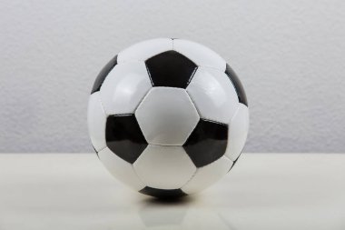 Masada klasik futbol topu, siyah-beyaz tipik altıgen desenli, gri arka planda izole. Gerçek, geleneksel futbol topu sembolü.