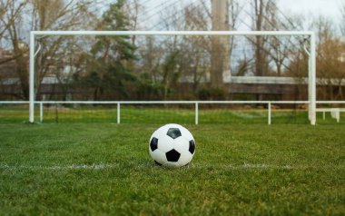 Stadyum kapısının önündeki serbest atış çizgisinde tipik bir futbol topu. Kaleden önce yeşil çimlerde geleneksel futbol topu.