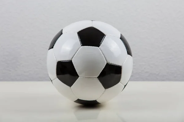 Classic football ball on the table, black and white typical hexagon pattern, isolated on  grey background. Real, traditional soccer ball symbol.