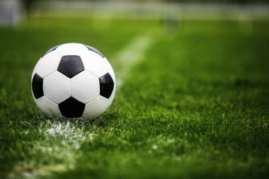 Klasik futbol topu, tipik siyah-beyaz desenli, stadyum sahasının beyaz çizgisi üzerine yerleştirilmiş. Yeşil çimlerin üzerinde fotokopi alanı olan geleneksel futbol topu.