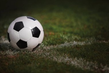 Klasik futbol topu, tipik siyah-beyaz desenli, stadyum sahasının beyaz çizgisi üzerine yerleştirilmiş. Yeşil çimlerin üzerinde fotokopi alanı olan geleneksel futbol topu.