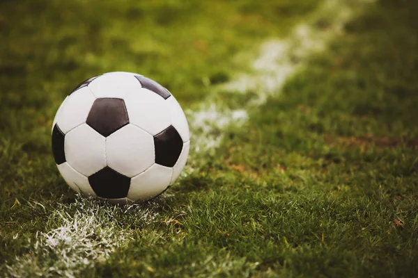 Klasik futbol topu, tipik siyah-beyaz desenli, stadyum sahasının beyaz çizgisi üzerine yerleştirilmiş. Yeşil çimlerin üzerinde fotokopi alanı olan geleneksel futbol topu.