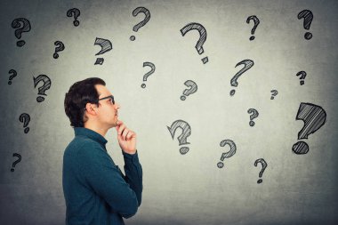 İşadamı elini çenesinin altında tutuyor, düşünceli bir jest, geleceğe bakıyor, kafasındaki farklı sorulara cevaplar düşünüyor. Sorgulama sembolleri. Düşünceli öğrenci çözümleri düşünüyor.