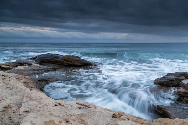 Хвилі падають на скелястий пляж — стокове фото