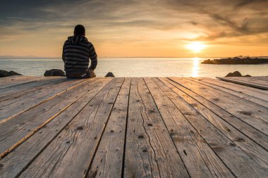 Adam oturur ve güneş ayarı izliyor