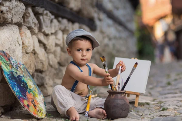 Pequeno pintor na rua de paralelepípedos — Fotografia de Stock