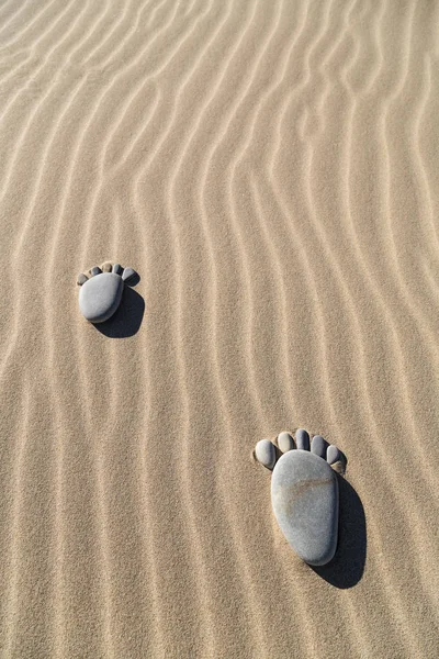 Fußabdruck aus Kieselsteinen im Sand — Stockfoto