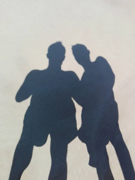 Long shadow of two friends on beach sand