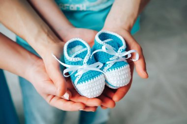 Anne ve baba elini tutarak yeni doğan bebek patik mavi