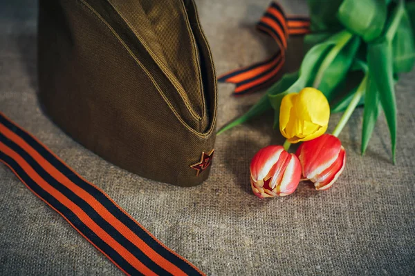 Military cap with order of Great Patriotic war and tulips flowers tied by Saint George ribbon