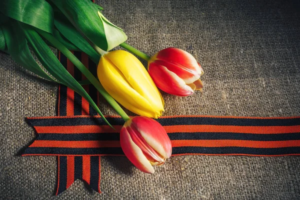 Военная шапочка с орденом Великой Отечественной войны и цветы тюльпанов, перевязанные Георгиевской лентой — стоковое фото