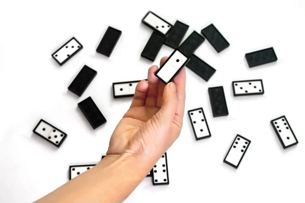 Piezas de dominó sobre fondo blanco. Mano sostiene dominó boca arriba — Foto de Stock