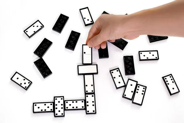 Piezas de dominó sobre fondo blanco. Mano sostiene dominó boca arriba — Foto de Stock