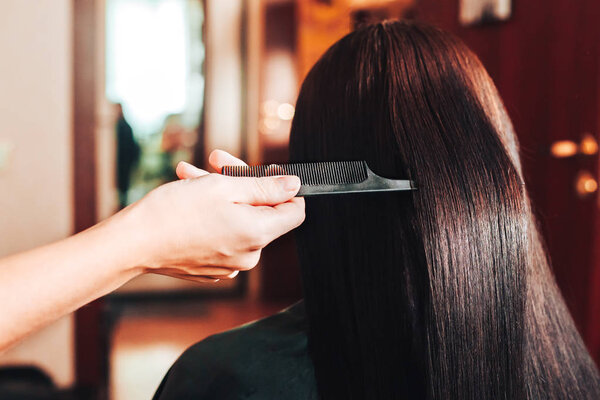 Молодая красивая женщина расчесывает волосы в парикмахерской
.
