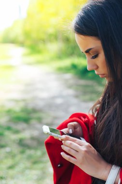 Kopya alanı ile bir parkta bir akıllı telefon kullanan mutlu kadın