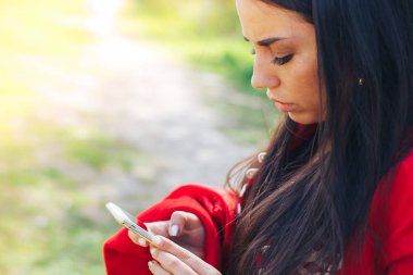 Kopya alanı ile bir parkta bir akıllı telefon kullanan mutlu kadın