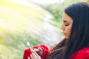 Kopya alanı ile bir parkta bir akıllı telefon kullanan mutlu kadın