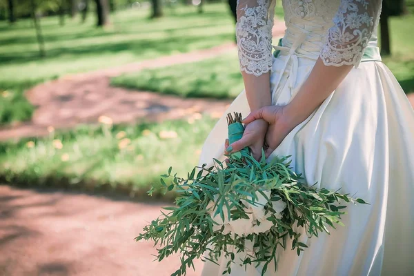신부는 보여주는 다시 그녀의 하얀 웨딩 드레스의 hemline 그녀의 손에 꽃다발과 함께 숲에 서 있다. 결혼식. 세부 정보 — 스톡 사진