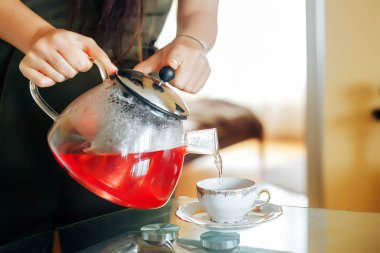 Ahududu çay. Kız bir su ısıtıcısı çay bir fincan içine dökülen.