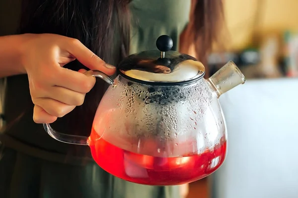 Raspberry tea. A girl holding a teapot with raspberry tea
