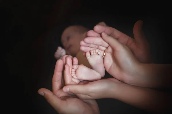 Mom and Dad hold baby legs. Taking care of a newborn.