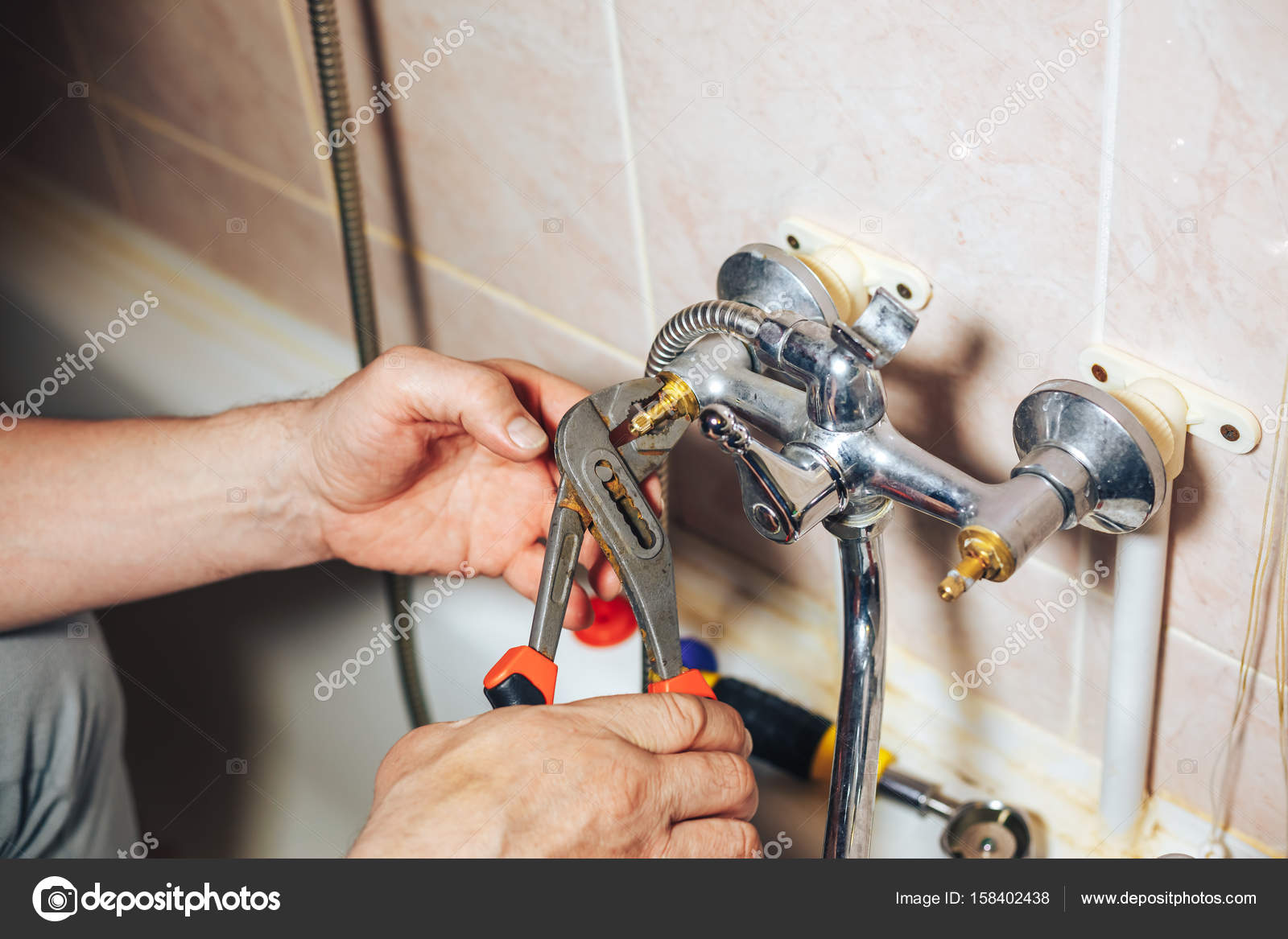 Man repair and fixing leaky old faucet in bathroom Stock Photo by