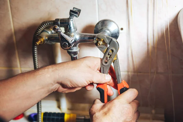 Человек ремонтирует и чинит протекающий старый кран в ванной комнате — стоковое фото