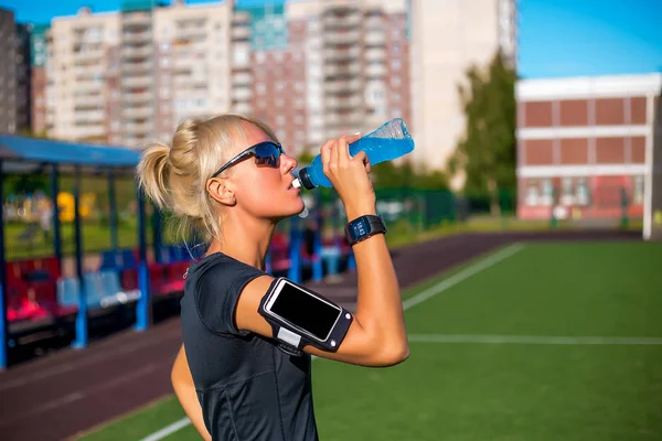 Sportif kadın içme suyu güneşli günde açık futbol Stadı — Stok fotoğraf