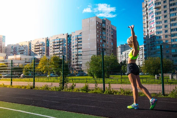 Genç fitness kadın runner uzanan eller önce stadyum üzerinde yaz günde çalıştırın. — Stok fotoğraf